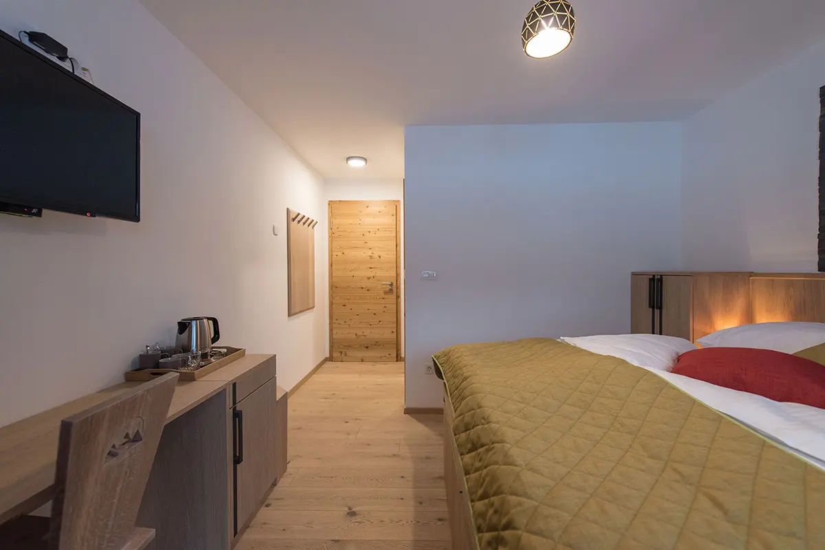 {"sl":"Sodobna hotelska soba z leseno opremo, dvojno posteljo, televizijo in \u010dajnikom na kredenci.","en":""}