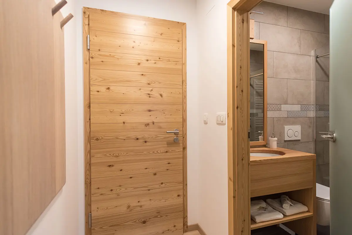 {"sl":"Lesena vrata in kopalnica s sodobnim umivalnikom in strani\u0161\u010dno \u0161koljko v ozadju.","en":""}